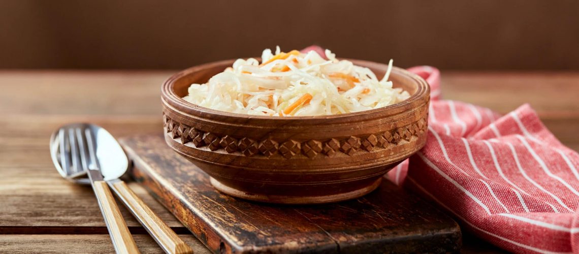 Sauerkraut, fermented cabbage with carrots in bowl on wooden background. Superfoods for support the immune system.